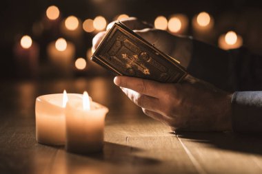 Religious man reading the Holy Bible and praying in the Church with lit candles, religion and faith concept clipart