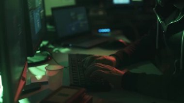 Siyah şapkalı hacker ile çalışan birden çok ekranlar ve kesmek sistemleri, siber suç ve güvenlik kavramı ile hoodie