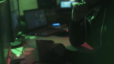 Siyah şapkalı hacker ile çalışan birden çok ekranlar ve kesmek sistemleri, siber suç ve güvenlik kavramı ile hoodie