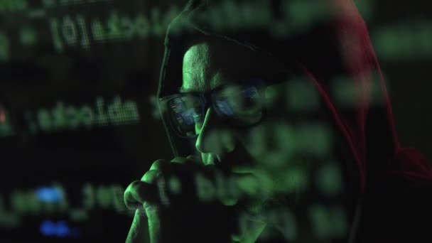 メガネとパーカーのハッカーは 彼はサイバー犯罪 コンピューターの画面上で実行し 概念をハッキングのコードを見ています — ストック動画