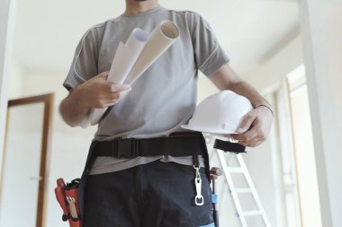 Holding kağıt rulo ve bir kask, ev yenileme ve mimari konsept profesyonel inşaat mühendisi