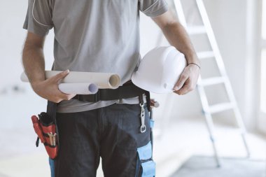Holding kağıt rulo ve bir kask, ev yenileme ve mimari konsept profesyonel inşaat mühendisi