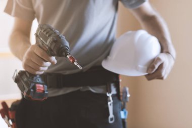 İnşaat işçisi kask ve matkap, ev yenileme ve inşaat kavramı ile poz