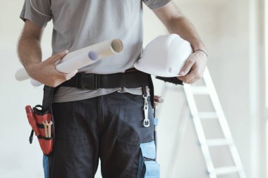 Holding kağıt rulo ve bir kask, ev yenileme ve mimari konsept profesyonel inşaat mühendisi