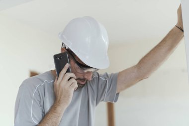 Profesyonel builder ile bir telefon görüşmesi, ev yenileme ve iletişim kavramı sahip güvenlik kask