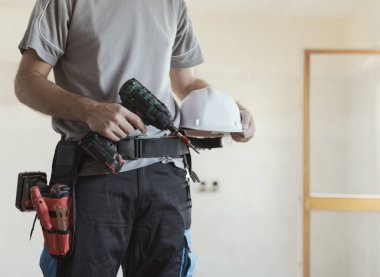 İnşaat işçisi kask ve matkap, ev yenileme ve inşaat kavramı ile poz