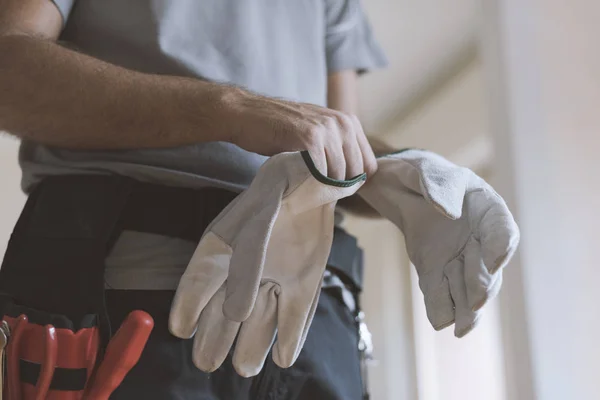 Professional repairman wearing protective gloves: home renovationa and safety concept