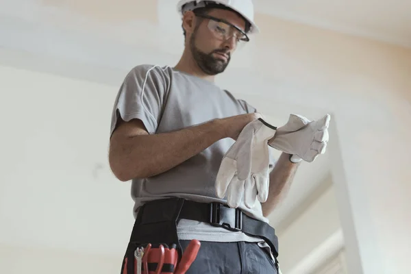Professional repairman wearing protective gloves: home renovationa and safety concept