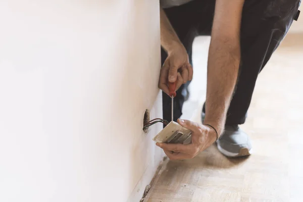 Professional electrician installing sockets using a screwdriver: home renovation and maintenance concept