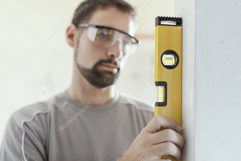 Man using a spirit level to plumb a wall: home renovation concept