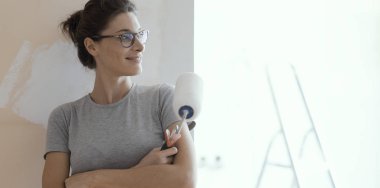 Bir rulo ile poz ve uzak seyir emin gülümseyen kadın: ev yenileme ve tadilat concept