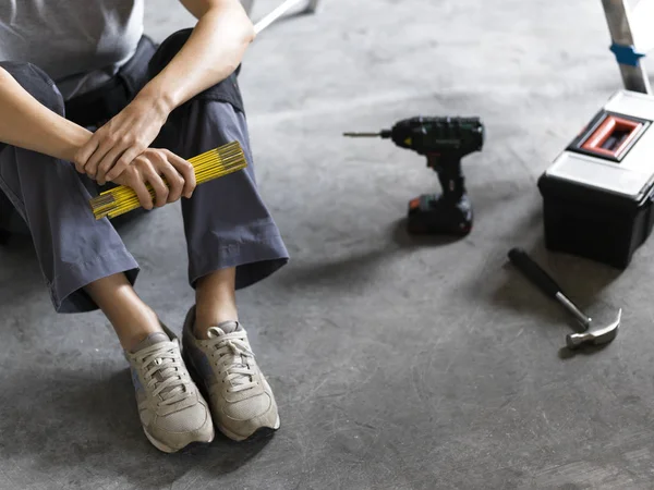 Γυναίκα Που Κάθεται Στο Πάτωμα Εργαλεία Και Κρατώντας Ένα Διπλώνοντας — Φωτογραφία Αρχείου