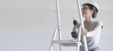 Bir matkap, ev yenileme ve DIY kavramı kullanan genç gülümseyen kadın