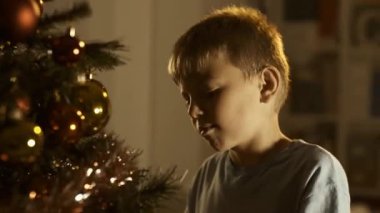 Evde, onun Noel ağacı süsleme şirin mutlu çocuk o Noel baubles ayarlama ve gülümseyen