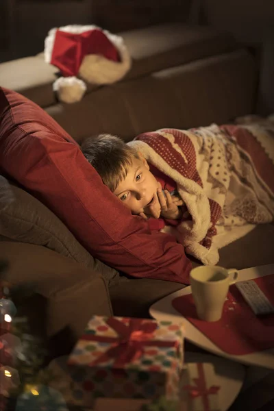 自宅のソファーで横になっていると クリスマス イヴのサンタを待っているかわいい男の子 子供との休日の概念 — ストック写真