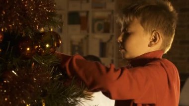 Onun Noel ağacı süsleme ve asılı mutlu çocuk topları, annesi oturma ve gülümseyerek: tatil ve Aile kavramı