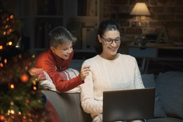 幸せな少年と母親のノート パソコンと接続し リビング ルーム フォア グラウンドでクリスマス ツリーの自宅で一緒に楽しんで — ストック写真