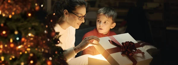 幸せな少年と彼の母親を開く魔法のクリスマス ギフト 家庭でフォア グラウンドでクリスマス ツリー 休日や家族の概念 — ストック写真