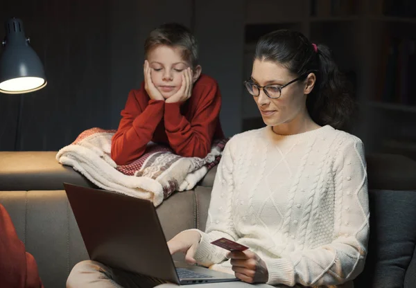 幸せな母と息子が一緒にノート パソコンを使用してオンライン ショッピングを行う 彼女はクレジット カードを保持しています — ストック写真
