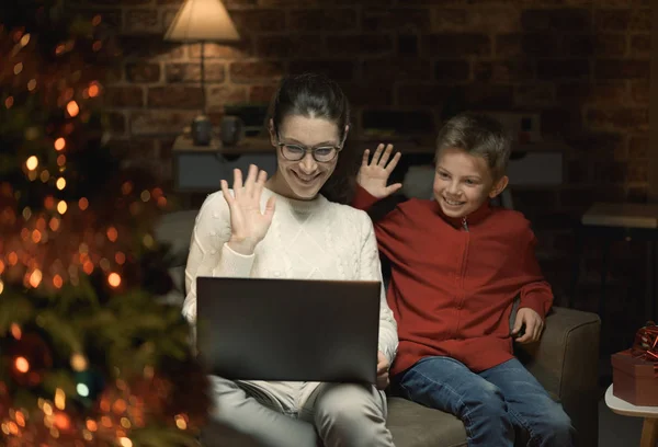 快乐的母亲和男孩与笔记本电脑联系 并有一个视频通话 他们挥舞着 并向朋友送去圣诞祝福 — 图库照片