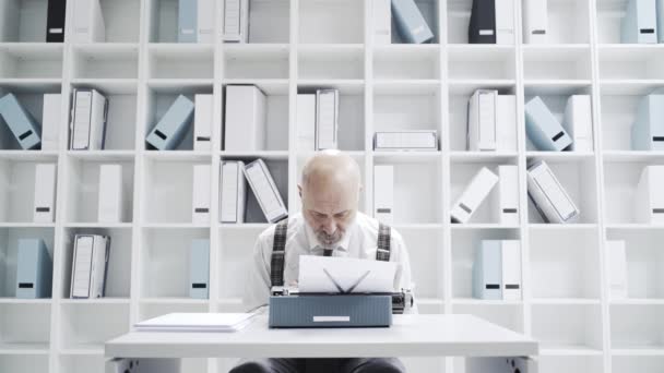 タイプライターでタイピング上級ビジネスマン彼が机の上に曲がっているとゆっくりと作業 — ストック動画
