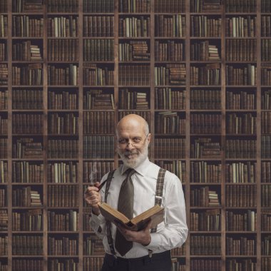 Üst düzey akademik Profesör kütüphanede eski bir kitap okuma: bilgi, öğrenme ve eğitim kavramı