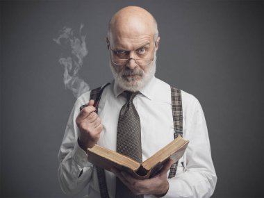 Confident senior professor smoking a pipe and reading an old book, knowledge and education concept clipart
