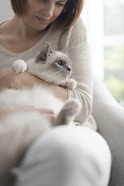 年轻快乐的女人坐在客厅的扶手椅上抚摸着她美丽的猫 — 图库照片