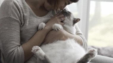 Holding ve onu güzel kedi sevişme genç mutlu kadın o karnını okşuyor