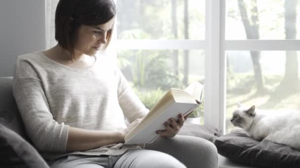 Oturma Odasında Rahatlatıcı Bir Kadın Koltukta Oturuyor Bir Kitap Okuma — Stok video
