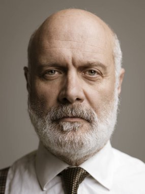 Gri arka plan üzerinde poz ve kameraya, bakan emin olgun işadamı headshot