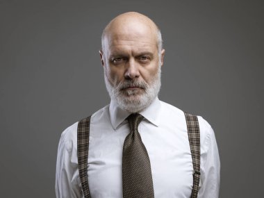 Ayakta ve poz, ciddi olgun iş adamı kendinden emin tavrı ile kameraya bakıyor