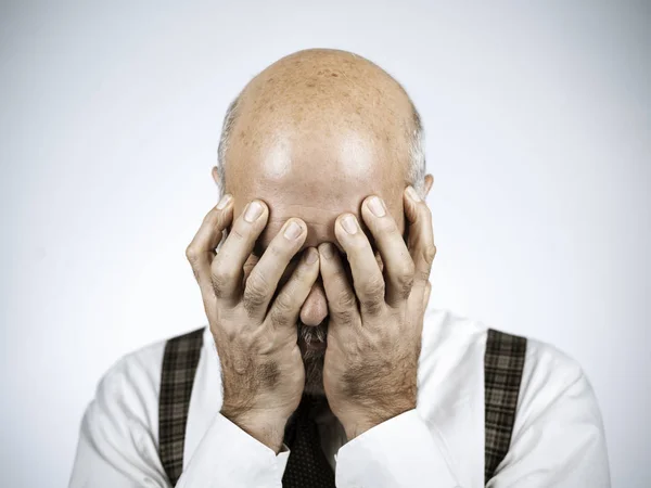 Desperate mature man with head in hands: he is feeling depressed, exhausted and hopeless