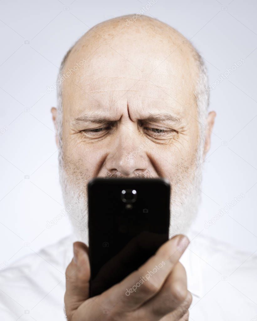 Senior man using apps on the smartphone, he is having difficulties and vision problems
