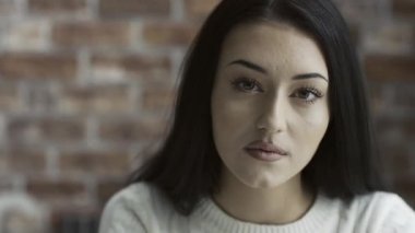 Poz ve gülümseyen, tuğla duvar içinde belgili tanımlık geçmiş Genç Sevimli Kadın