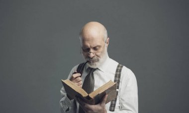 Kendine güvenen kıdemli Profesör pipo ve eski bir kitap okuma: bilgi ve eğitim kavramı