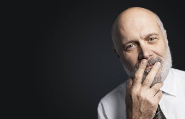 Onun yüzünde bir el ile poz ve kameraya bakarak olgun adam