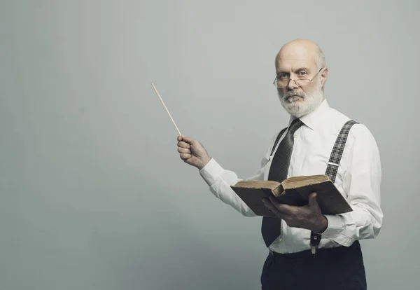 Senior academic professor giving a lecture and pointing at the empty blackboard using a stick: knowledge and traditional education concept