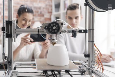 Mühendisliği öğrencileri, prototip modeller 3d yazıcı kullanarak yazdırma kız bir akıllı telefon ile fotoğraf çekmek ve online paylaşım