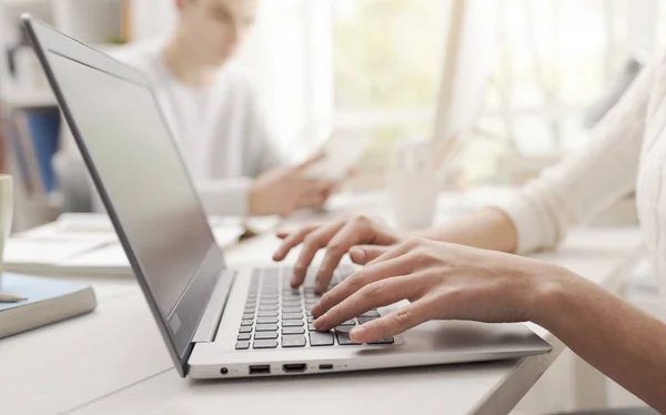 ノート パソコンとの接続 別の学生をしている女の人は バック グラウンドで机に座って 手をクローズ アップ — ストック写真