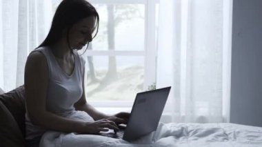 Mutlu kadın yatakta yatan ve online onu laptop kullanarak bağlanma