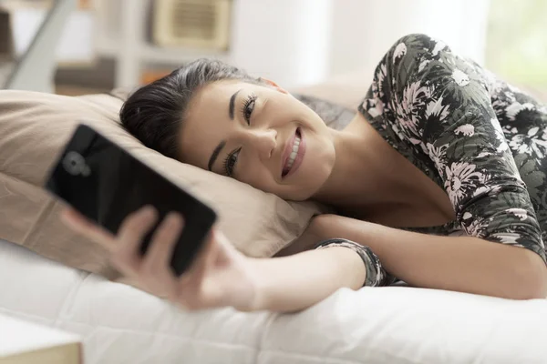 Jeune Femme Souriante Détendant Sur Lit Connectant Avec Son Smartphone — Photo