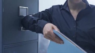 Kendine güvenen bir dosya dolabı yanında duran ve bir dosya holding iş kadını gülümseyen, o kameraya gülümsüyor