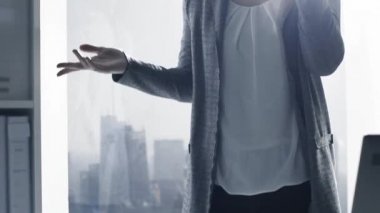 Bir pencere yanında duran ve onun smartphone, iş ve iletişim konsepti ile bir telefon görüşmesi sahip emin kurumsal iş kadını