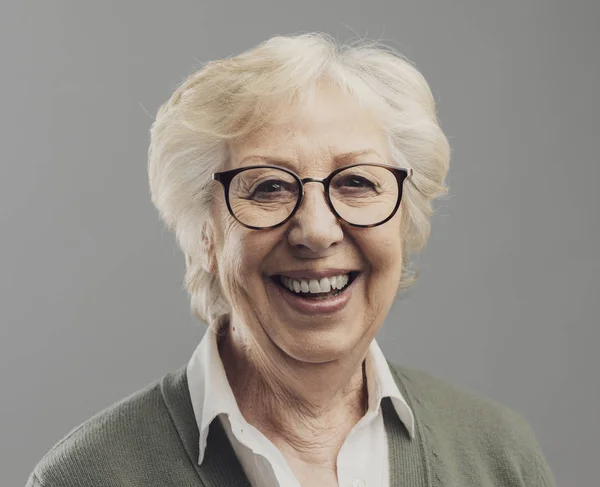 Glückliche Seniorin posiert auf grauem Hintergrund — Stockfoto