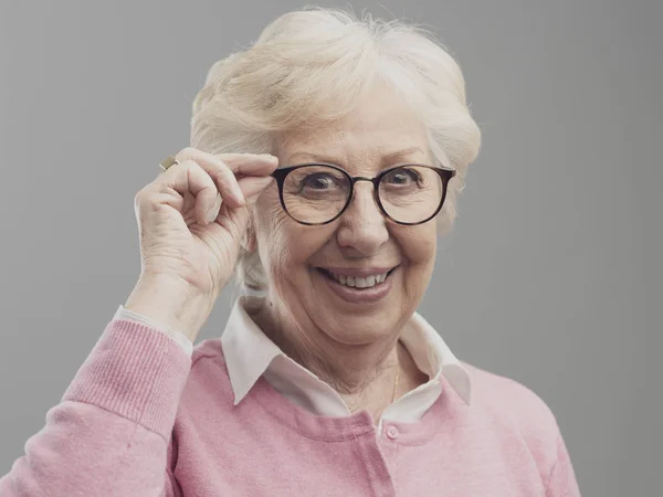Feliz señora mayor posando y mostrando sus gafas — Foto de Stock