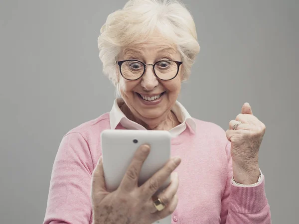 Feliz sorprendida señora mayor usando una tableta digital —  Fotos de Stock