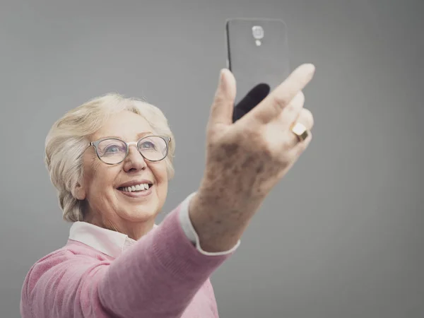 Щаслива старша жінка бере селфі зі своїм смартфоном — стокове фото