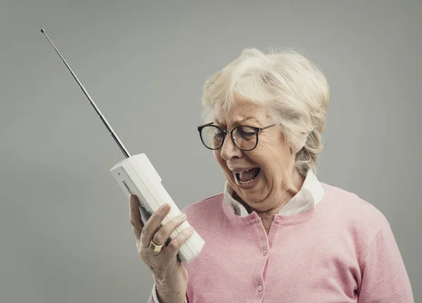 Gefrustreerd senior vrouw met behulp van een oude telefoon — Stockfoto