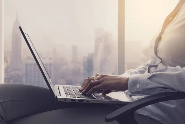 Empresária trabalhando com um laptop ao lado de uma janela — Fotografia de Stock